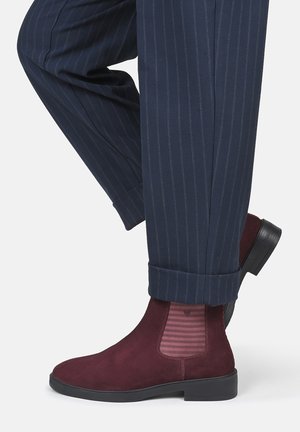 Navy pinstripe trousers rolled at the cuff paired with burgundy suede Chelsea boots with striped elastic side panels.