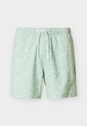 Pantalones cortos de baño verde claro con patrones geométricos tropicales blancos y una cintura con cordón blanco.