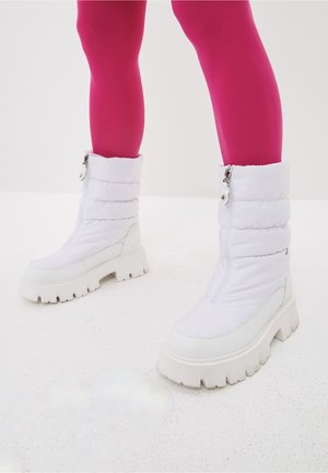 Bottes blanches de style doudoune avec une semelle épaisse, dotées d'une fermeture éclair et d'un haut replié. Matériau texturé avec des accents lisses.