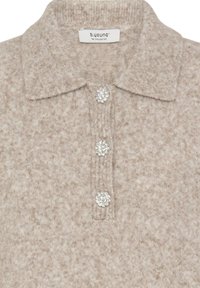 Bežs adīts polo tops ar apkakli, kas aprīkots ar trim dekoratīvām kristāla pogām priekšpusē un mīkstu, strukturētu audumu.