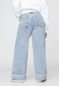 Svetlomodré široké rifle z denimu so zrolovanými lemy, s klasickým päťvreckovým dizajnom a jemným vyblednutím po celej ploche.