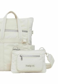 Bolsa tote de tela blanca con bolsillo con cremallera y asas cortas, acompañada por un pouch más pequeño con cremallera y correa ajustable.