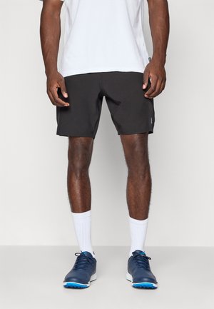 Sorte idrettsshorts med elastisk midje, kombinert med hvite sokker og marineblå sportssko. Glatt tekstur, ingen synlige mønstre.