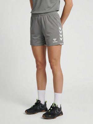 Person trägt graue Hummel-Sportshorts, weiße Kniestrümpfe und schwarze Laufschuhe mit grauen und neon-grünen Akzenten.