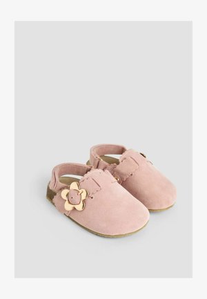Růžové semišové boty pro malé děti s květinovým zlatým akcentem, otevřeným střihem na zadní straně, vlnkovým prošíváním a texturovanou gumovou podrážkou.