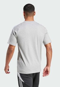 Grijze t-shirt met korte mouwen en ronde halslijn, gemaakt van een gladde stof, met contrasterende witte strepen op de schoudernaden.
