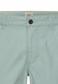 Helle blaue Shorts aus weichem Stoff mit Knopfverschluss, Gürtelschlaufen und dezenten Nähten an der Vorderseite und am Bund.