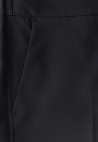 Svart tyg med en slät yta, med en sidoficka och minimalistisk design, verkar lämplig för olika avslappnade eller formella sammanhang.