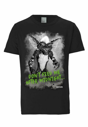 Schwarzes Baumwoll-T-Shirt mit einem gremlin Grafik in Schwarz und Weiß sowie grünem Text, der "FÜTTER MICH NICHT NACH MITTERNACHT..." lautet.