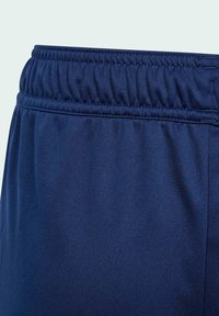 Detalle de cinturilla elástica en pantalones de tejido azul marino, que muestra la costura y el material gather para mayor ajuste y comodidad.