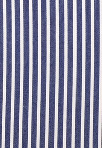 Tessuto blu con strisce bianche verticali equidistanti, creando un classico motivo a righe.