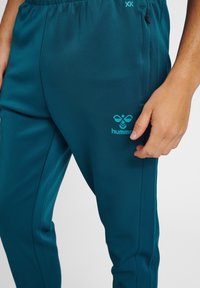 Teal sportbroeken met een elastische tailleband en logo op de dij, gemaakt van een gladde, lichte stof en met details op de zijnaad.