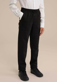 Pantaloni în carouri negre cu talie elastică și șnur ajustabil, buzunare laterale și un design croit. Asortați cu teniși negri.