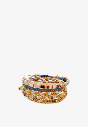 Ein Stapel bunter gewebter und mit Perlen verzierter Armbänder in Blau-, Beige-, Braun- und Goldtönen, die in einer kreisförmigen Anordnung auf weißem Hintergrund liegen.