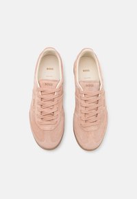 Pink suede sneakers with lace-up closure, rounded toe, and gum sole. Features embossed brand logo and smooth inner lining.