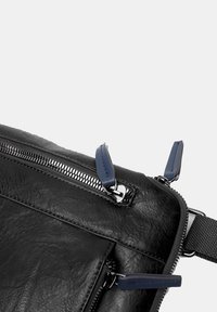 Borsa in pelle nera con superficie testurizzata, zip argentata con tirazip in pelle blu e una robusta tracolla in tessuto.