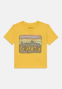 Gelbes Baumwoll-T-Shirt mit einem grafikdesign von Bergen und dem Schriftzug "Patagonia" in Braun. Kurze Ärmel und Rundhalsausschnitt.