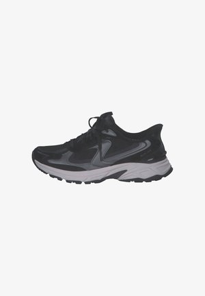 Zapatilla deportiva negra y gris con cordones en la parte delantera, suela gruesa texturizada y paneles de malla transpirables para soporte y comodidad.