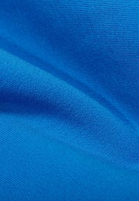 Blauwe stof met een gladde textuur, die fijne brei details en een levendige tint toont, gerangschikt in plooien en vouwen.