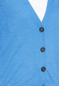 Blauer Strickcardigan mit V-Ausschnitt, fünf schwarzen Knöpfen auf der Vorderseite und glatter Textur. Keine weiteren Muster oder Akzente sichtbar.