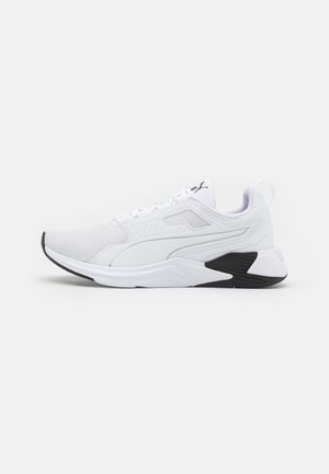 Biały sportowy sneaker z siateczkową cholewką, wiązaniem na sznurówki i czarnymi detalami podeszwy, widoczny z lewej strony na białym tle.