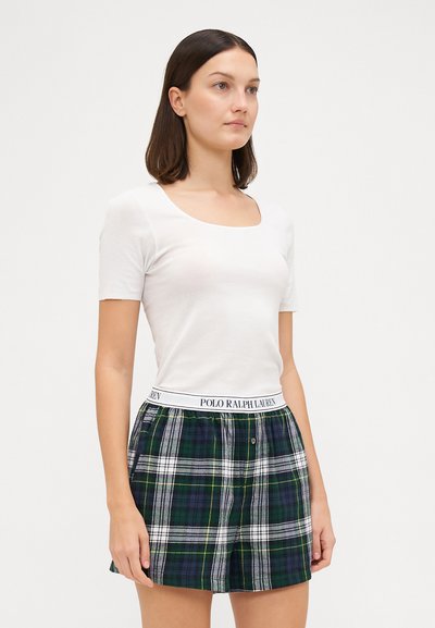 Bílý tričko s krátkým rukávem v kombinaci se zeleno-modrými kostkovanými šortkami s bílým pasem označeným "POLO RALPH LAUREN."