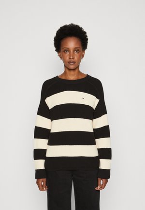 Maglione a righe nere e crema con una texture a coste, caratterizzato da un collo rotondo e una vestibilità comoda. Il maglione ha maniche lunghe e un piccolo dettaglio con logo.