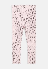 Lichtroze legging met een geribbelde structuur en zwarte polka dots. Het ontwerp heeft een aansluitende pasvorm en een elastische tailleband.