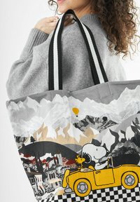Grau Stoffeinkaufstasche mit einem grafischen Design eines Autos, Bergen und einer Figur mit einem Hund. Schwarz-weiße gestreifte Träger.