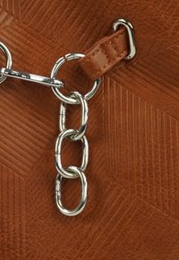 Brązowa skórzana tekstura z geometrycznym wzorem, z metalowym łańcuszkiem w kolorze srebrnym i brązowym skórzanym paskiem.