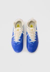Scarpe da calcio blu con materiale sintetico texturizzato, dettagli in crema, sei fori per i lacci e logo giallo sul lato. Chiusura con lacci.