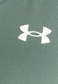 Zelená prúžkovaná tkanina s bielym logom Under Armour v strede. Dizajn má hladkú textúru a priliehavý strih.