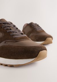 Baskets marron en daim et mesh, avec bout rond, laçage à l'avant, semelle rembourrée et détails en caoutchouc contrastés.