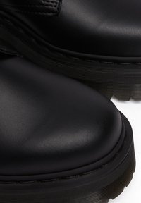 Zwarte leren laarzen met een gladde textuur, ronde teen, dikke rubberen zool en gedetailleerde stiksels langs de rand.