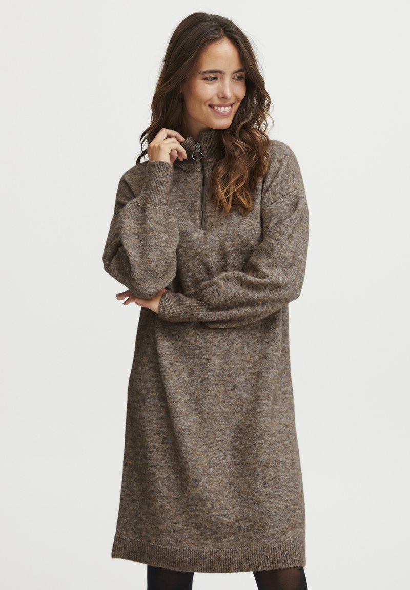 Robe pull en tricot brun avec un col haut et une fermeture à demi-zippée. Dotée de manches longues et d'une coupe décontractée, se terminant juste au-dessus des genoux.