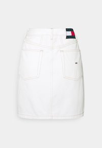 Gonna di denim bianca con taglio dritto, due tasche posteriori, cuciture chiare e una patch con il marchio sulla cintura che presenta colori rosso, verde e blu.