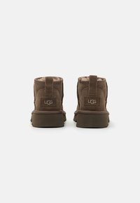 Botas de tobillo de ante marrón con un forro suave, punta redondeada y parte trasera texturizada. Con un lazo para facilitar su uso y suela plana de goma.