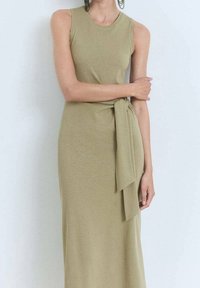 Hihaton oliivinvihreä mekko, joka on valmistettu pehmeästä kankaasta ja jossa on edessä solmittava yksityiskohta. Slim fit -malli, nilkkapituinen design pyöreällä kaula-aukkolla.