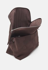 Ruskea kangaspäinen vetoketjullinen laukku, jossa on kuvioitu tekstuuri ja sileä vuori; siinä on tilava sisätila ja pieni ulkotasku.