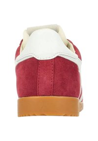 Sneaker in suede rosso con un tab sul tallone in pelle bianca, caratterizzate da una suola in gomma e un semplice design a strisce lungo il lato.