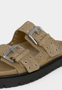 Ταμπά σουέντ σανδάλι με χοντρή μαύρη σόλα, δύο ασημένιες αγκράφες και πολλαπλές μεταλλικές οπές σε ρυθμιζόμενους ιμάντες.