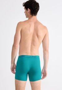 Teal men's boxers with a soft, stretchy texture. The waistband features the brand logo and provides a snug fit.