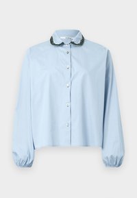 Lyseblå skjorte med knapper og rund krave med mørkegrøn broderet kant, lange ærmer med elastiske manchetter og kort pasform.