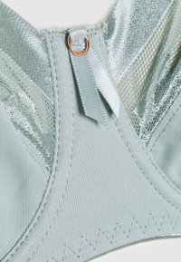 Sutiã azul claro com um tecido liso e acabamentos brilhantes. Possui um fecho de gancho, costura decorativa e um acabamento suave e texturizado.