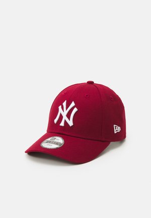 Casquette de baseball rouge en tissu, avec un logo brodé blanc sur le devant et un petit emblème blanc sur le côté. Visière courbée.