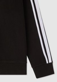 Manica di felpa nera con strisce laterali bianche, dettagli a costine ai polsi, tessuto morbido e un design pulito e sportivo.