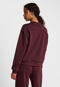 Bordeaux sweatshirt met een relaxed fit, ribbels aan de mouwen en een ronde hals; gemaakt van een zachte, gestructureerde stof. Het achterontwerp heeft een naaddetail.