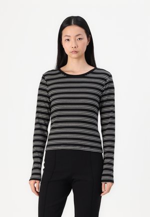 Black and white striped long-sleeve top with a rounded neckline, fitted design, and soft texture, paired with black trousers.