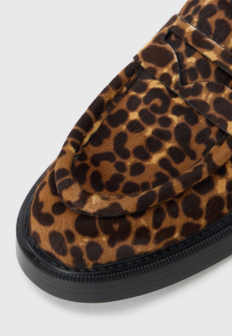 Mocassini con stampa leopardata e texture morbida, caratterizzati da una punta arrotondata e suola in gomma nera. I dettagli includono cuciture eleganti.