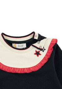 Katoenen shirt met een marineblauwe body, een crèmekleurige kraag met rode franje en geborduurd sterdetail. Drukknoopsluiting op de schouder.